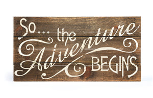 "So The Adventure Begins" brown wooden crate sign.