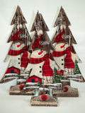 Wooden Christmas tree featuring a friendly snowman behind a wintery, glittery scene. Sets on a wood base with a snow drift. 
